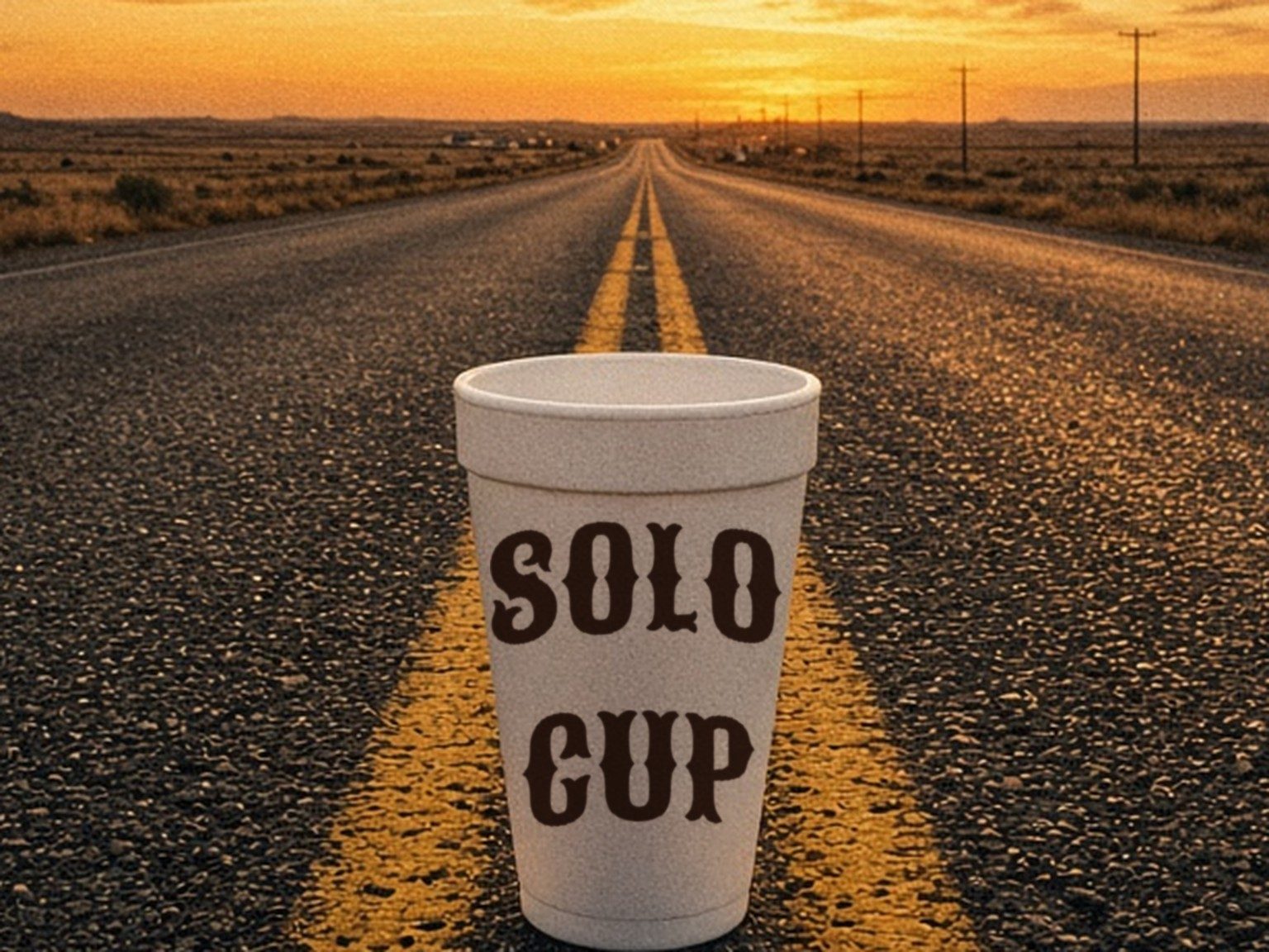 A foam cup sitting on the yellow line of an empty Texas highway at sunset